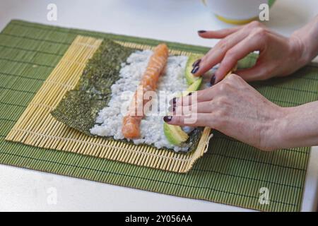 Woman rolling sushi with bamboo mat Stock Photo