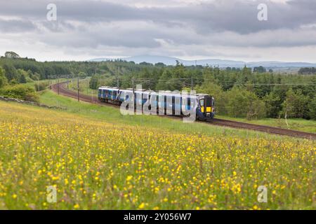 Treno elettrico multiunità ScotRail Siemens classe 385 che passa per la campagna di Auchengray, Scozia, Regno Unito Foto Stock