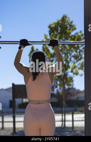 Giovane ragazza che fa esercizio calistenico nei bar all'aperto. esercizio di pull-up Foto Stock