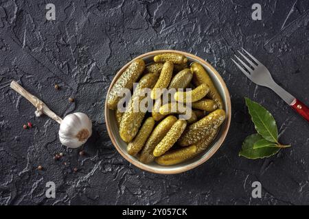 Cetrioli sottaceto con aglio e foglia di alloro. Alimenti fermentati. Cetriolini fatti in casa. Immagine orizzontale sopra la testa su sfondo di ardesia nera Foto Stock