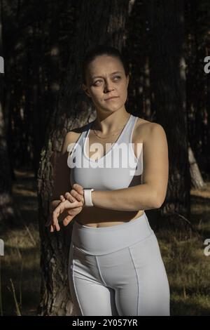 Giovane ragazza sportiva che guarda uno smartwatch che si allena all'aperto alla luce del sole Foto Stock