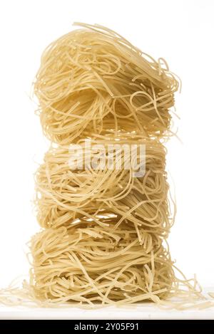 Tre palline di pasta tipo spagehetti molto fine e sottile, note come "Angel's Hair" in Italia, sono impilate, una sopra l'altra, e su una bianca isolata Foto Stock