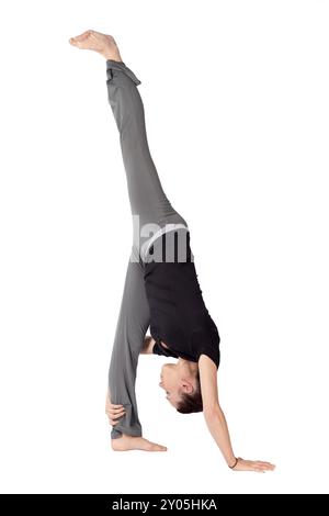 Giovane donna in forma che fa Standing Split yoga asana (nome sanscrito: Urdhva Prasarita Eka Padasana), isolata su sfondo bianco Foto Stock