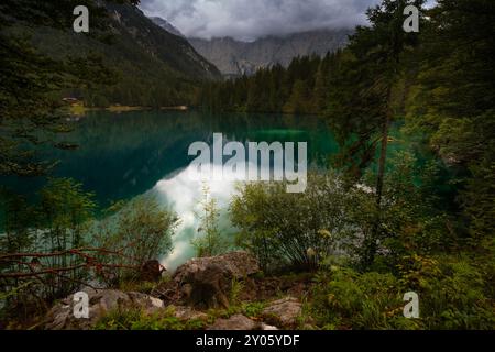 Vista panoramica mattutina sul Lago di Fusine vicino al confine tra Italia e Slovenia. Incantevole lago con incredibili acque profonde e colorate e foresta nebbiosa intorno. Foto Stock