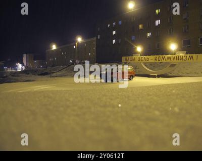 Appartamenti, auto e il comunismo segno nella neve durante la notte, Barentsburg, Spitsbergen Foto Stock