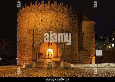 Varsavia Barbican di notte in Polonia, porta ad arco della città Vecchia, parte della fortificazione delle mura della città vecchia Foto Stock