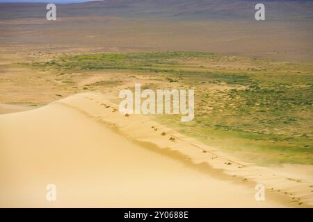 Vento che soffia granelli di sabbia a partire dal bordo superiore della Khongor Els Dune di sabbia nel deserto del Gobi in Mongolia Foto Stock