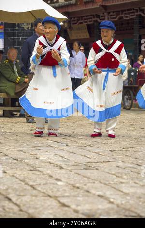 Lijiang, Cina, 30 settembre 2017: Due donne anziane Naxi vestite in costume tradizionale danzando in una piazza nella città vecchia di Lijiang, Yunnan, Cina, Asia Foto Stock