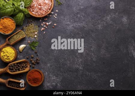 Spezie ed erbe su fondo di pietra nera. Vista dall'alto con spazio libero per menu o ricette Foto Stock