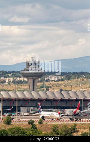 Madrid, Spagna; 05-18-2024: Torre di controllo dell'aeroporto Adolfo Suarez Madrid Barajas vicino al terminal con imbarco aereo della compagnia Latam Foto Stock