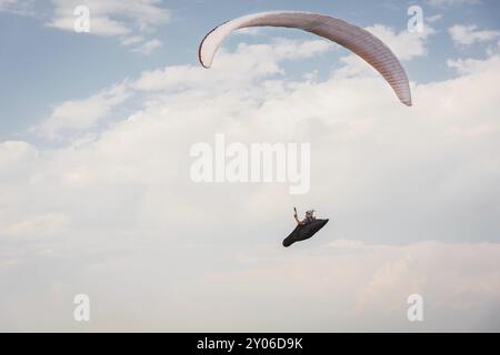 Parapendio da solo che vola nel cielo blu sullo sfondo delle nuvole. Parapendio nel cielo in una giornata di sole Foto Stock