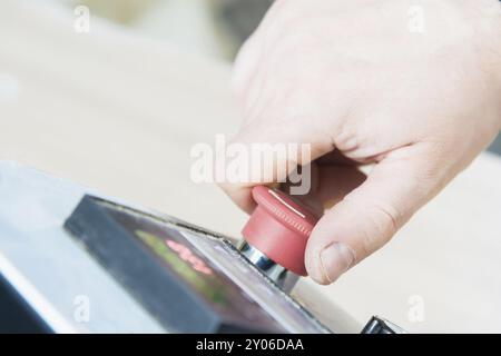 Primo piano della mano di un uomo su un pulsante rosso sul pannello di controllo. Arresto di emergenza o avvio di attrezzature e produzione Foto Stock