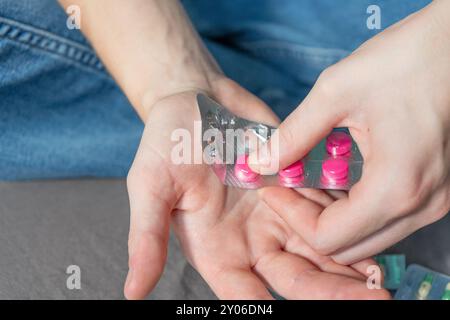 Ragazza che regge le pillole. Pillole di diversi colori in una mano. Scuotere le pillole dal flacone. Estrarre le pillole dalle bolle delle pillole. Foto Stock