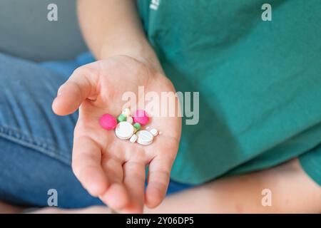 Ragazza che regge le pillole. Pillole di diversi colori in una mano. Scuotere le pillole dal flacone. Estrarre le pillole dalle bolle delle pillole. Foto Stock