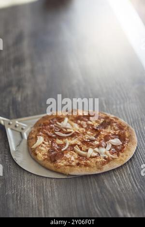 Appena cotto alla griglia di fiamma pizza italiana su una crosta croccante su un contatore di legno in una pizzeria con copia spazio sopra Foto Stock