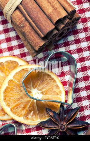 Arancia, cannella, anice e taglierina per biscotti su un panno a scacchi Foto Stock