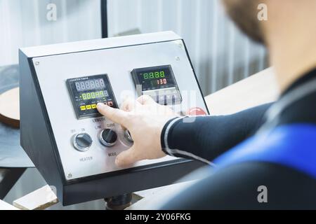 Primo piano dell'operatore, l'operatore preme il pulsante sul pannello di controllo con i dispositivi di controllo nella produzione di mobili. La mano di quell'uomo presse Foto Stock