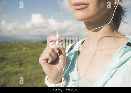 Primo piano della faccia inferiore di una giovane runner in natura prima di fare jogging. Chin e labbra sorridenti della sportiva e mano sul microfono di Foto Stock