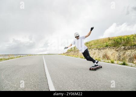 Il giovane esegue un trucco complesso chiamato scivolo sul longboard Foto Stock