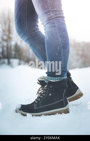 Ragazza in jeans blu è trekking in inverno, gambe e scarpe Foto Stock