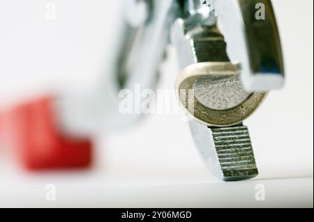 Un euro piegato tra le ganasce di un paio di pinze con curvatura concava Foto Stock