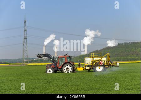 Il trattore con rimorchio irrora l'agente di protezione prodotto su un campo di grano Foto Stock