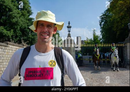 Windsor, Berkshire, Regno Unito. 1 settembre 2024. La campionessa olimpica Etienne Stott MBE, della Extinction Rebellion parla ai manifestanti fuori dal Castello di Windsor. Centinaia di manifestanti per il clima della ribellione dell'estinzione si sono recati oggi a Windsor, Berkshire, come parte del loro weekend di protesta di tre giorni a Windsor. Marciarono dal loro accampamento a Home Park attraverso le strade fino al Castello di Windsor, dove tennero una manifestazione e attirarono visitatori e residenti. XR afferma che “l’Upgrade Democracy riguarda la ribellione contro i fallimenti sistemici del governo e le bugie che creano un sistema ingiusto. Foto Stock