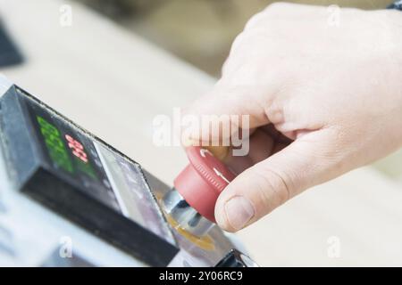 Primo piano della mano di un uomo su un pulsante rosso sul pannello di controllo. Arresto di emergenza o avvio di attrezzature e produzione Foto Stock