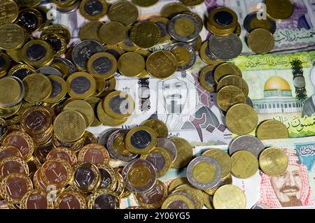 Monete di riyal saudita, 2, 1, mezza e un quarto di moneta su banconote in denaro saudita di riyal banconote, di diversi valori, moneta ed economia Foto Stock