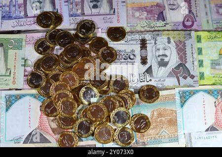 Monete di un riyal saudita su banconote in denaro saudita di riyal banconote, di diversi valori, denaro e stato economico della valuta, incl Foto Stock