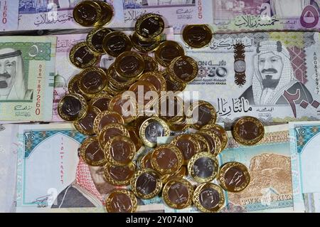 Monete di un riyal saudita su banconote in denaro saudita di riyal banconote, di diversi valori, denaro e stato economico della valuta, incl Foto Stock