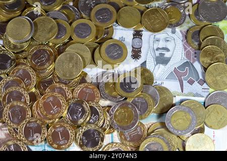 Monete di riyal saudita, 2, 1, mezza e un quarto di moneta su banconote in denaro saudita di riyal banconote, di diversi valori, moneta ed economia Foto Stock