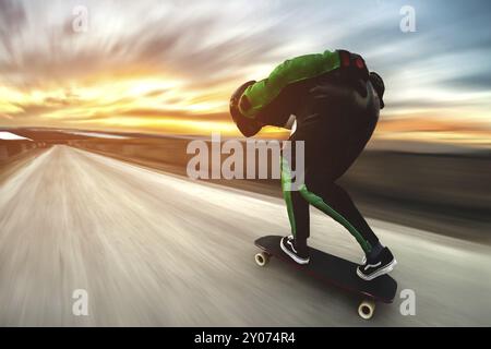 Un uomo con casco e tuta in pelle, in una speciale cremagliera ad alta velocità, cavalca su una lunga longboard per scendere in discesa a galla sullo sfondo di un beauti Foto Stock