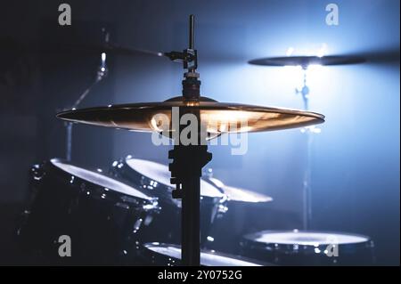 Primo piano tamburo in una stanza buia contro lo sfondo del riflettore. Sfondo atmosferico simbolo della musica rock o jazz. Piastre in rame su Foto Stock