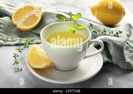 Un primo piano di una tazza di tè verde con limoni ed erbe aromatiche Foto Stock