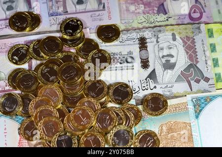 Monete di un riyal saudita su banconote in denaro saudita di riyal banconote, di diversi valori, denaro e stato economico della valuta, incl Foto Stock