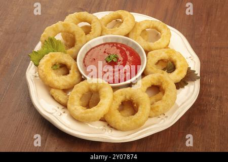 Un primo piano foto di anelli di totano con una salsa di pomodoro al buio su un sfondo di legno Foto Stock