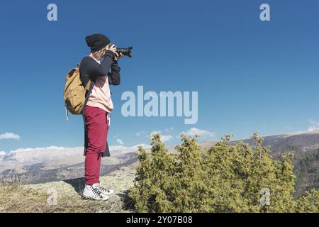 Natura fotografo scattare foto sulla sua fotocamera dslr all'aperto durante il viaggio escursionistico sul Caucaso. Caucaso settentrionale Russia Foto Stock