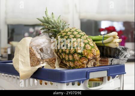 Un cestino della spesa pieno di generi alimentari in cucina Foto Stock