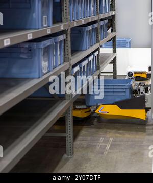 Robot autonomo che preleva i materiali da rack multistrato in un moderno magazzino industriale. Foto Stock