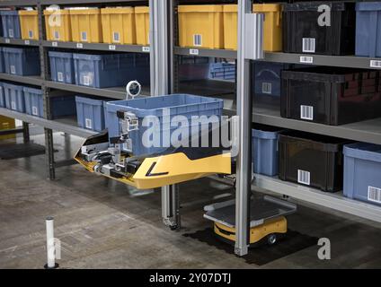 Robot autonomo che preleva i materiali da rack multistrato in un moderno magazzino industriale. Foto Stock