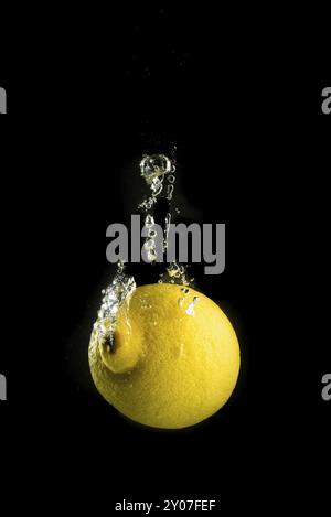 Frutta limone schizzi in acqua e affondamento isolati su sfondo nero Foto Stock