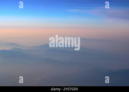 Vista aerea di rosa e blu del tramonto, alba sulle montagne sagome, scattato dall'aereo Foto Stock