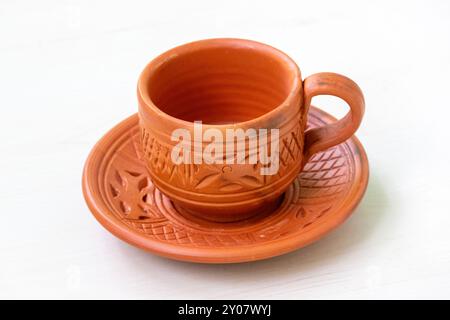 Bella tazza e piatto in argilla posizionati su una superficie di legno chiaro. Foto Stock