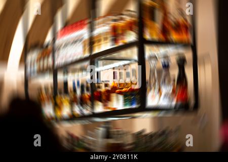 Una vista delle bottiglie di liquore viene visualizzata in un bar con un effetto di sfocatura del movimento in stato di ubriachezza. Foto Stock