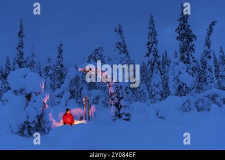 Man around a Campfire, Muddus National Park, Laponia, Patrimonio dell'Umanità, Norrbotten, Lapponia, Svezia, gennaio 2016, Europa Foto Stock