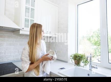 Donna felice di fare il lavaggio fino in cucina Foto Stock