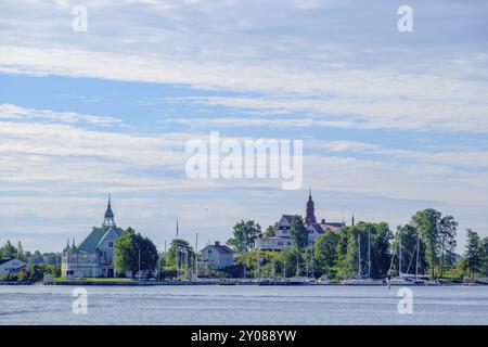 Vista di un porto con case e barche sotto un cielo blu, circondato da alberi e una passeggiata sul lungomare, Helsinki, Finlandia, Europa Foto Stock