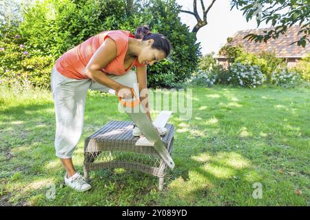 Giovane donna colombiano segatura di legno con handsaw outdoor Foto Stock