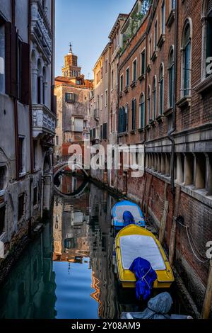 Stretto canale con barche sul lato nel quartiere San Marco di Venezia in Italia. Foto Stock